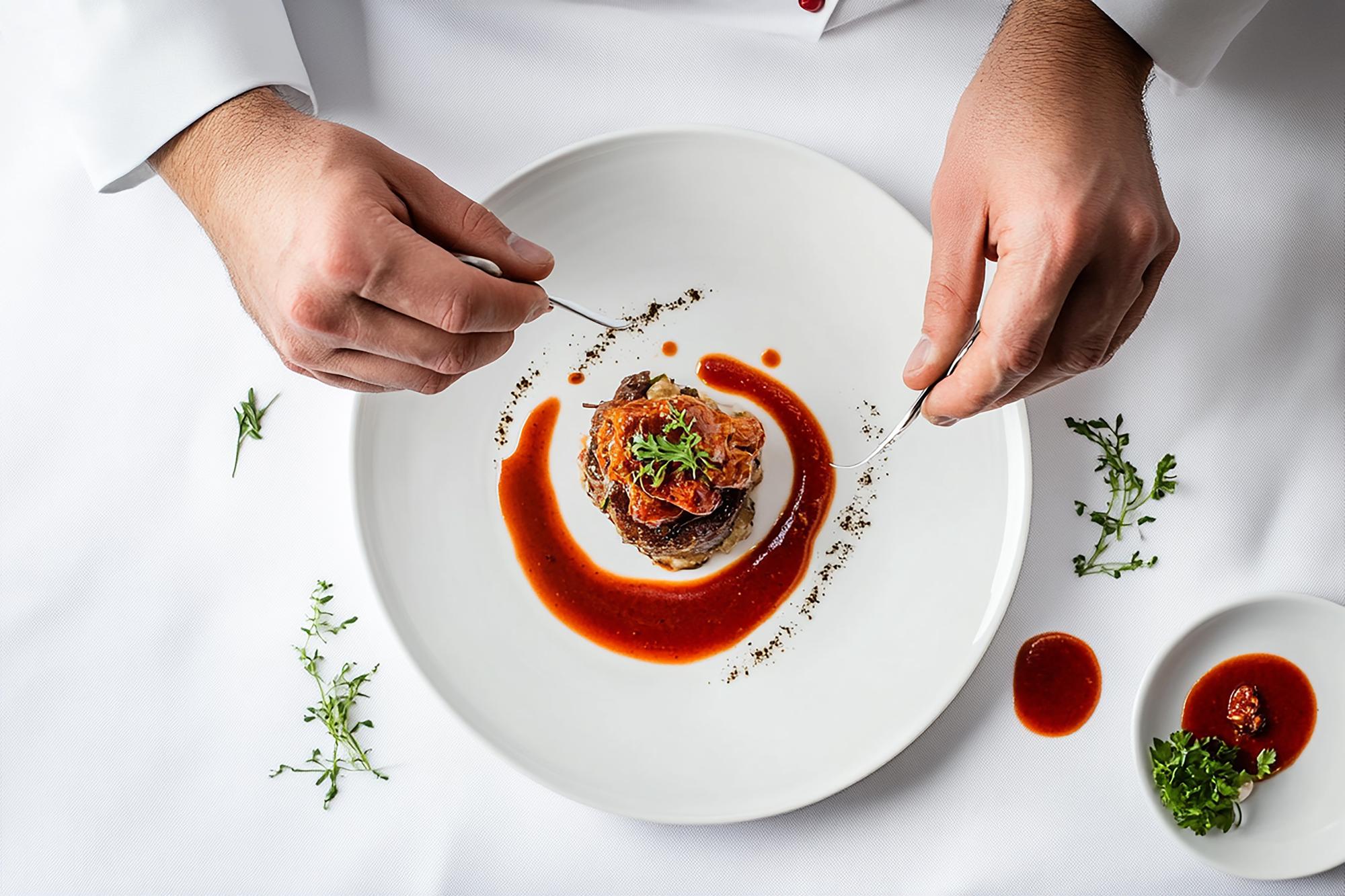 Chef preparing plated gourmet dish in elegant kitchen